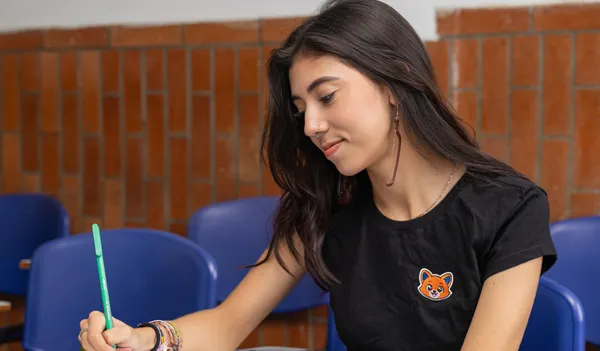 Estudiante de Pre ICFES Superior escribiendo en el salón